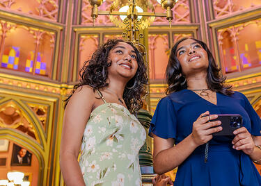 Two travelers look at cathedral-like stained glass inside Louisiana's Old State Capitol.